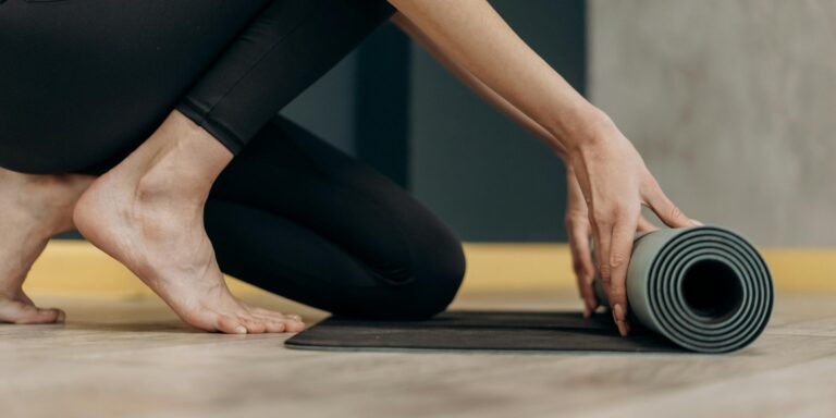 L'image présente une personne qui déroule un tapis de yoga.