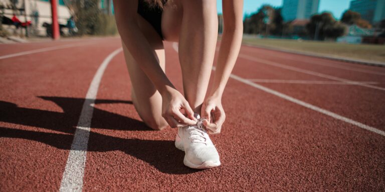 L'image présente une personne qui attache son soulier sur une piste de course.